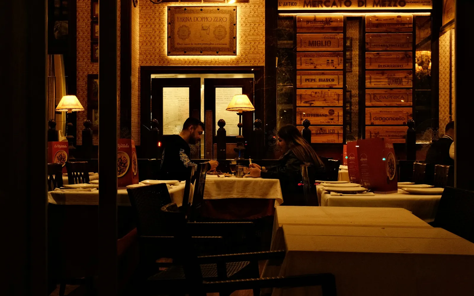 A small independent bistro at night, its back wall stacked with wine crates