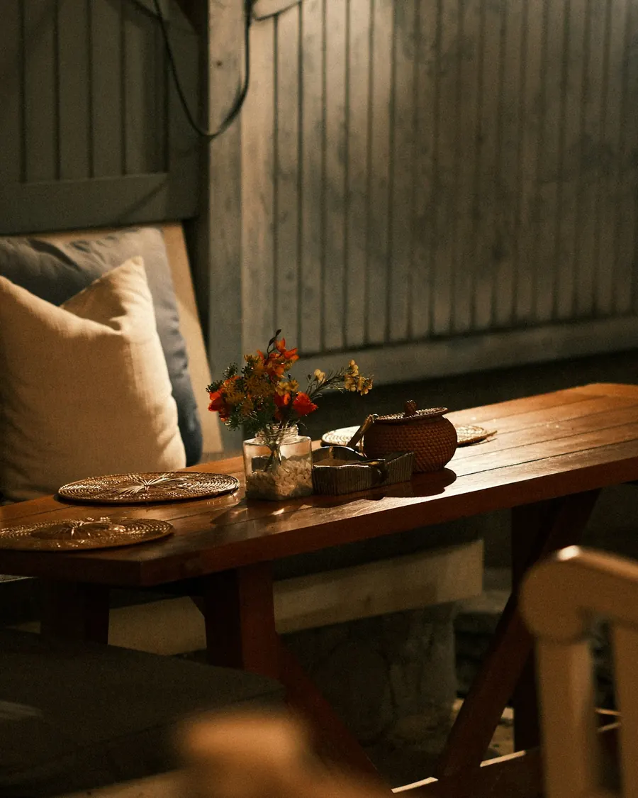 A wooden table laid for service with flowers and simple place settings
