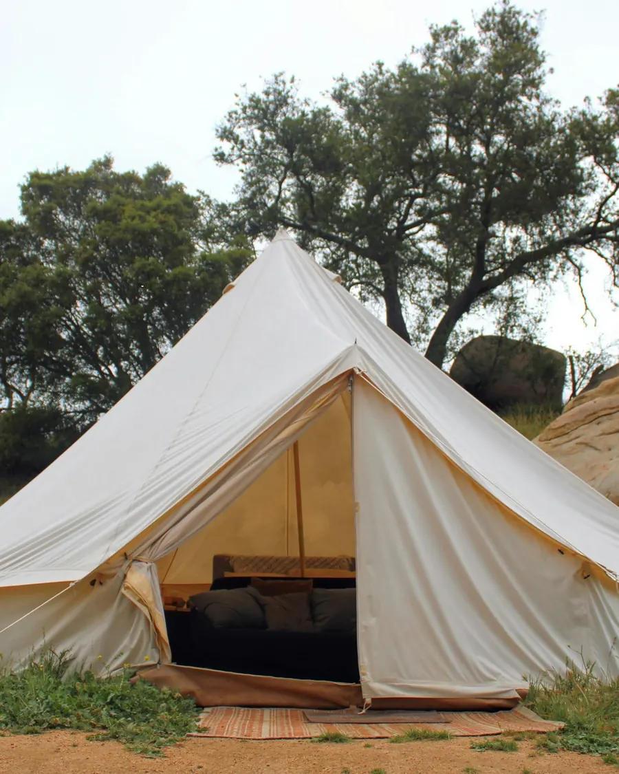 A white canvas bell tent pitched in a quiet meadow