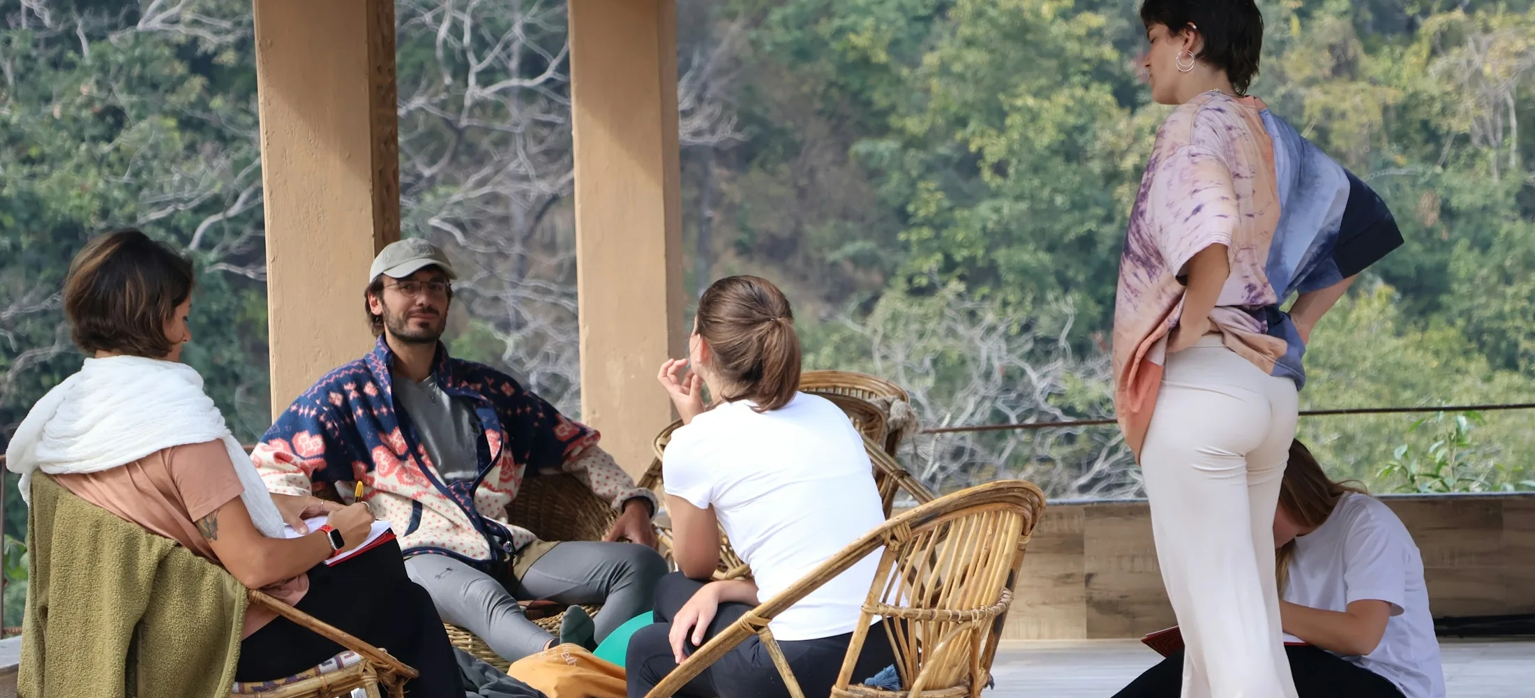 A small retreat group talking together on a covered porch above a wooded valley
