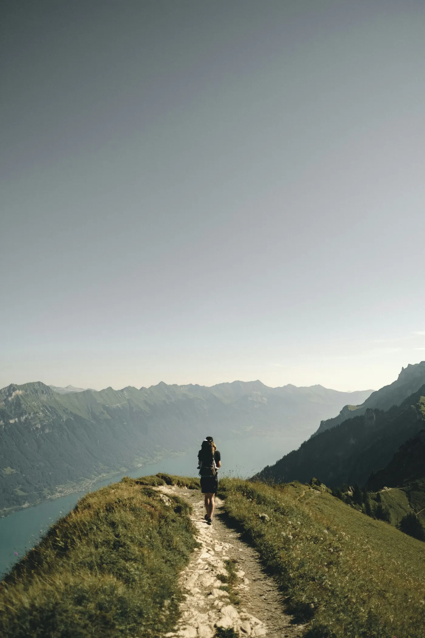 A walker on a ridge path high above a mountain lake
