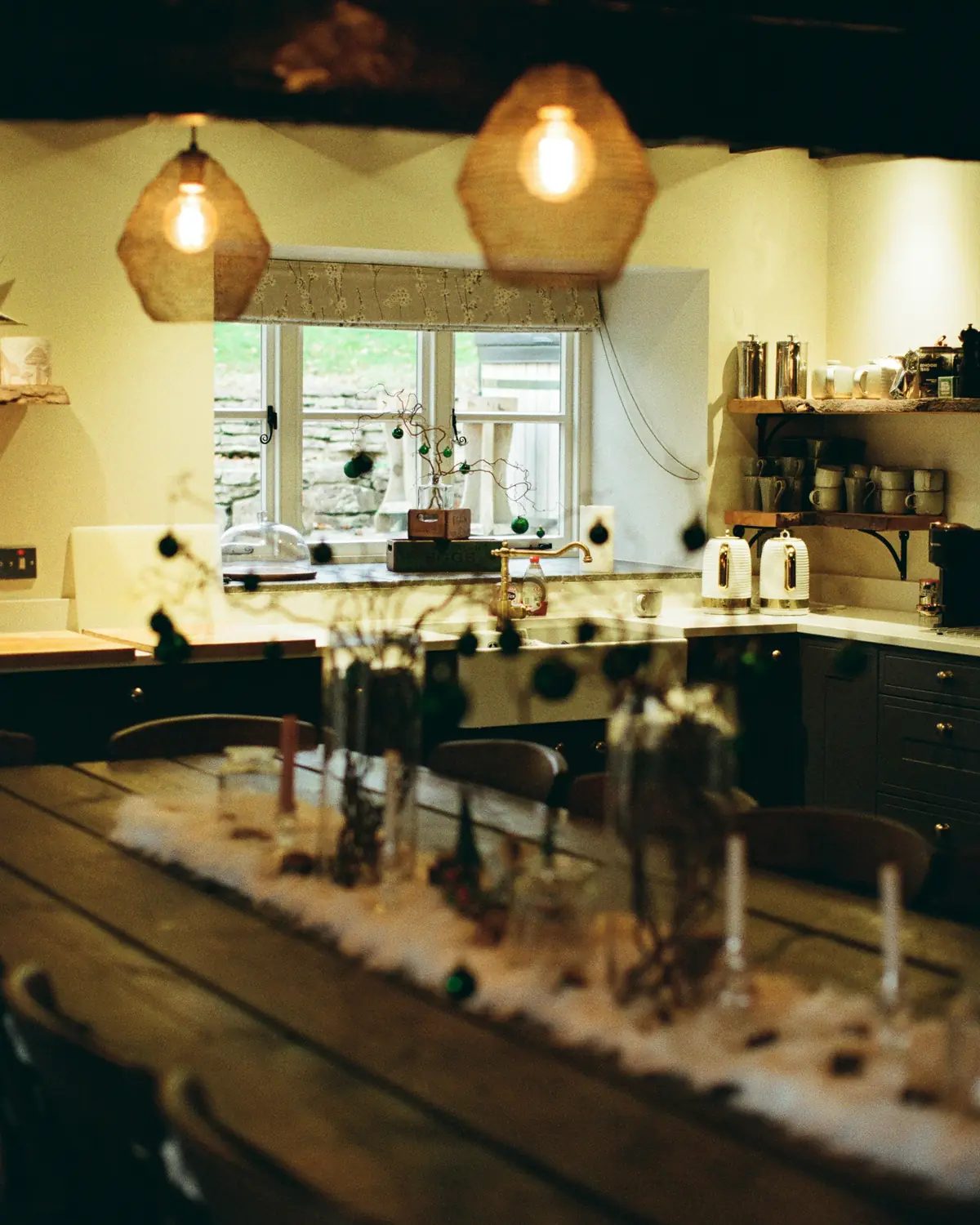 A rustic cottage kitchen with a long table and pendant lights