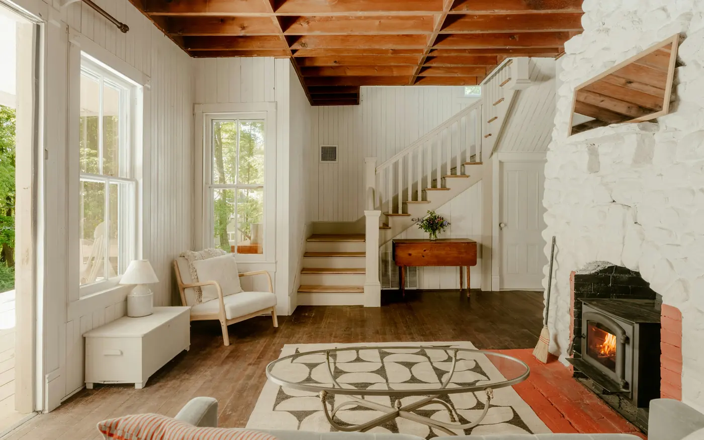 A bright cottage living room with a wood burner and exposed beams