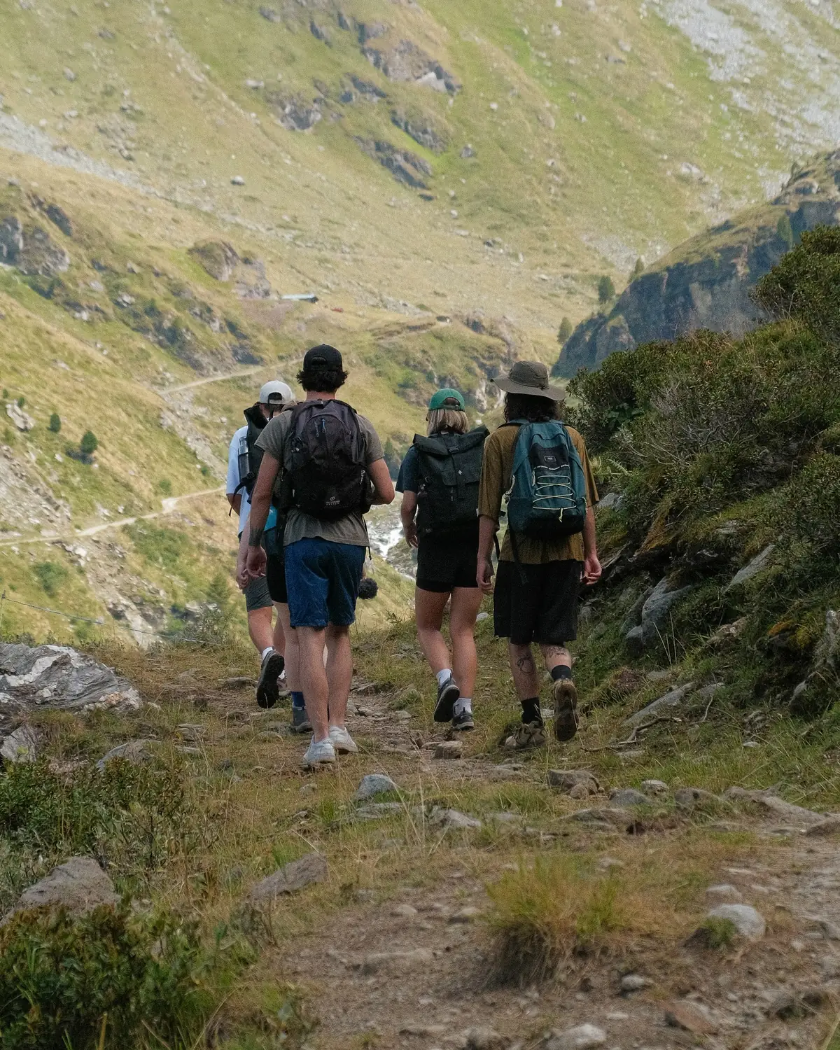 Walkers on a narrow mountain trail above a valley
