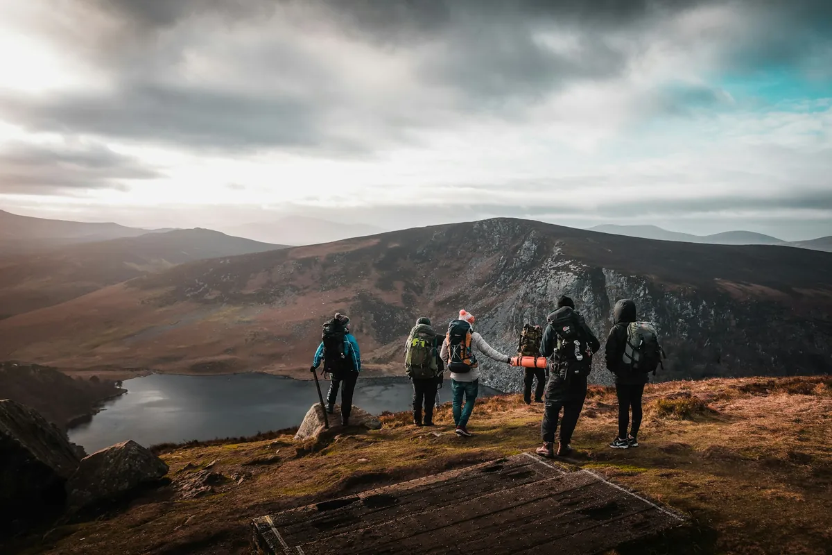 A small guided group walking a high ridge above a lough